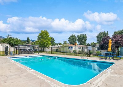 Swimming pool and sundeck with tables at Timpanogos Village MHC in Orem City, Utah